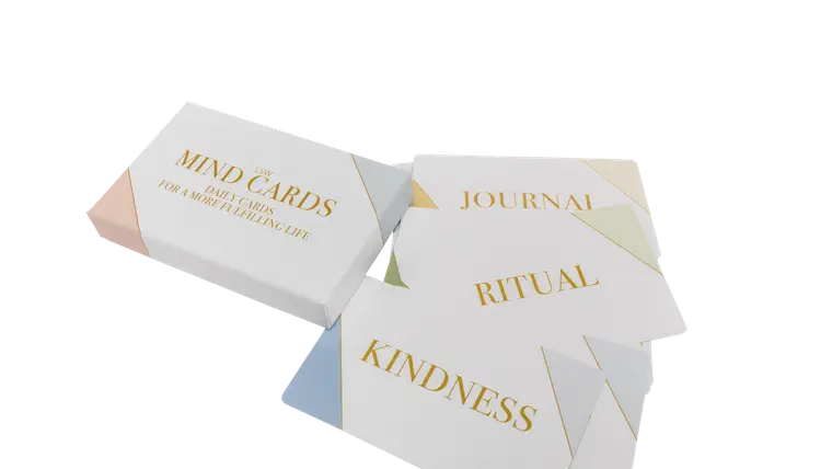 A wellbeing gift collection with a candle, a reusable bottle, tea and a soft blanket arranged on a linen surface.